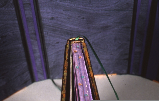 The top & bottom of the book was gilded w/variegated copper. Top of the book was painted w/purple acrylic then goffered with a star pattern & each star hand painted. The head band is of red copper wire and green silk. The page marker is of green silk.